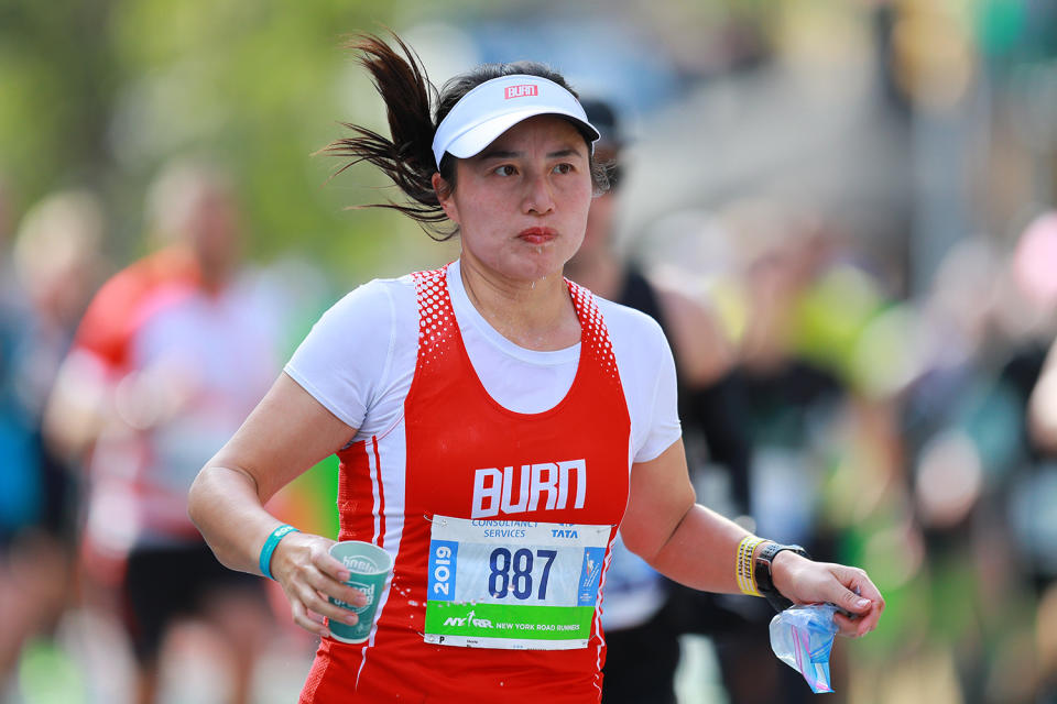 A participant carries a cup of water while running up First Avenue during the 2019 New York City Marathon. (Photo: Gordon Donovan/Yahoo News)