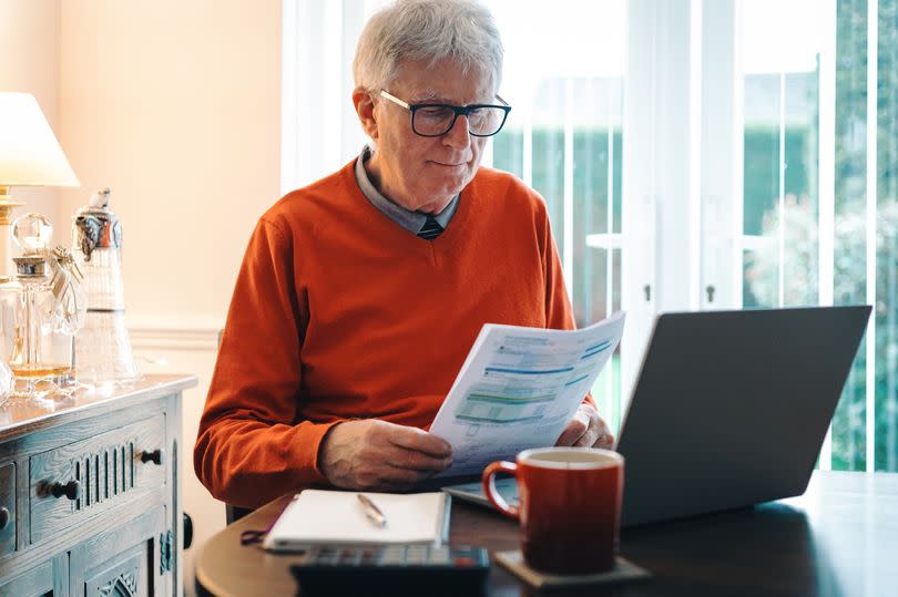 A worried male pensioner checks his household bills