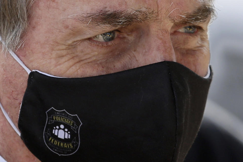 FILE - In this May 26, 2020 file photo, Brazil's President Jair Bolsonaro, wearing a face mask with a logo of the Federal Police, leaves his official residence of Alvorada Palace in Brasilia, Brazil. Bolsonaro won the presidency in 2018 with a campaign that emphasized law and order, and said police should be able to kill criminals with almost no legal constraints in order to curb homicides. (AP Photo/Eraldo Peres, FIle)