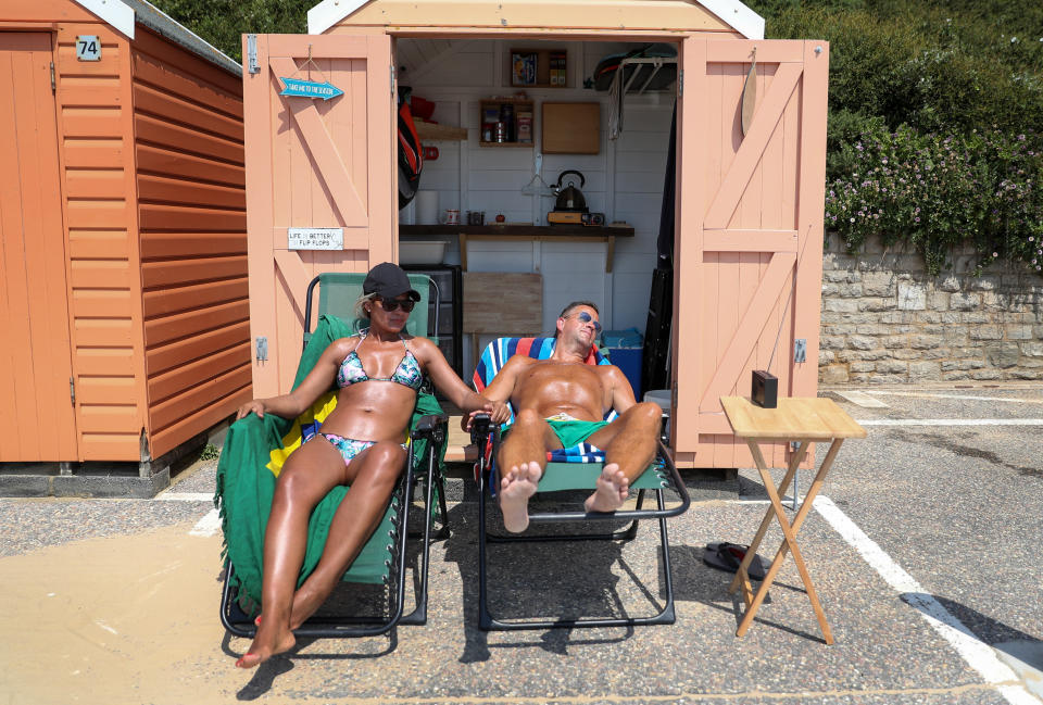 A couple relax outside their beach hut on the beach in Bournemouth, Dorset.