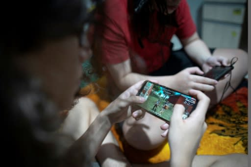 Brothers Guilherme (L), 14, and Arthur, 11, play the mobile game Free Fire at their house in Rio de Janeiro, Brazil