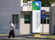 FILE - In this Nov. 3, 2019, file photo, a man walks past a compound for Saudi Aramco in Jiddah, Saudi Arabia. Saudi Arabia's state-owned oil company Aramco on Thursday, Dec. 5, set a share price for its IPO, that puts the value of the company at $1.7 trillion, more than Apple or Microsoft. (AP Photo/Amr Nabil, File)