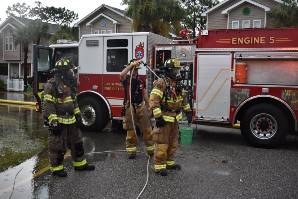 South Walton Fire District firefighters hose each other down after responding to a fire at a home on Enchanted Way in Santa Rosa Beach. The fire was believed to be caused by a lightning strike.