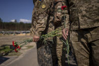 Irpin Territorial Defence and Ukrainian Army soldiers hold flowers to be placed on the graves of fallen comrades during the Russian occupation, at the cemetery of Irpin, on the outskirts of Kyiv, on Sunday, May 1, 2022. (AP Photo/Emilio Morenatti)