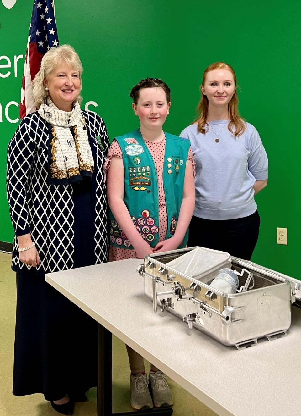 Eve Whittenburg, Y-12 historian, surprises Gracie Ogle at her award ceremony March 16 with an authentic moon box used by NASA. With them is Girl Scouts of Southern Appalachians CEO Lynn Fugate, left.