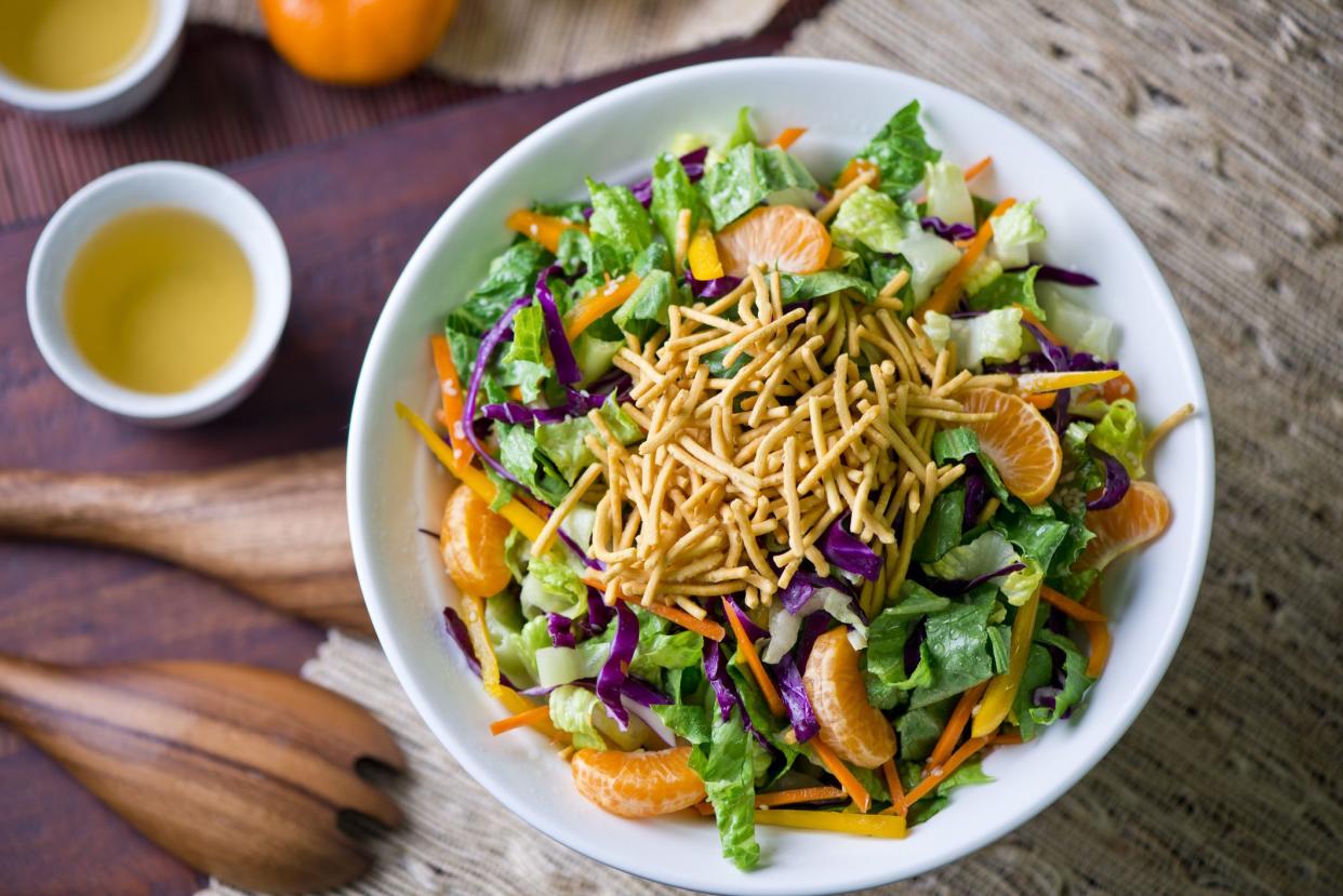 Salad with Mandarin oranges. Traditional Chinese salad with thinly sliced ribbon lettuce, red cabbage, carrots and fried crispy wonton noodles. Cuisine served on Chinese New Years.