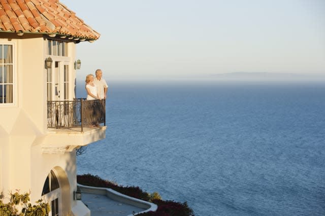 Senior couple on balcony of house overlooking ocean