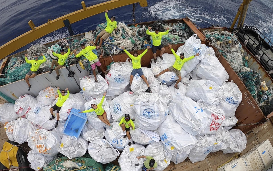 In this April 21, 2021 photo provided by Andy Carre, workers with the Papahanaumokuakea Marine Debris Project pose on top of fishing nets and plastics collected from the the beaches of the Northwestern Hawaiian Islands before offloading the marine debris in Honolulu. A crew has returned from the remote Northwestern Hawaiian Islands with a boatload of marine plastic and abandoned fishing nets that threaten to entangle endangered Hawaiian monk seals and other marine animals on the tiny, uninhabited beaches stretching for more than 1,300 miles north of Honolulu. (Andy Carre, Papahanaumokuakea Marine Debris Project via AP)