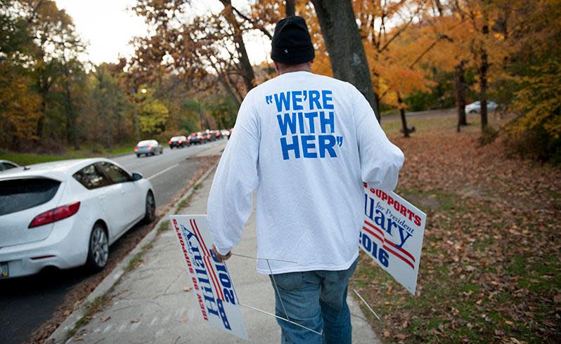 "I'm with her": A volunteer places signs in support of Hillary Clinton in the 2016 US presidential election after polls opened in Philadelphia. Photo: AAP