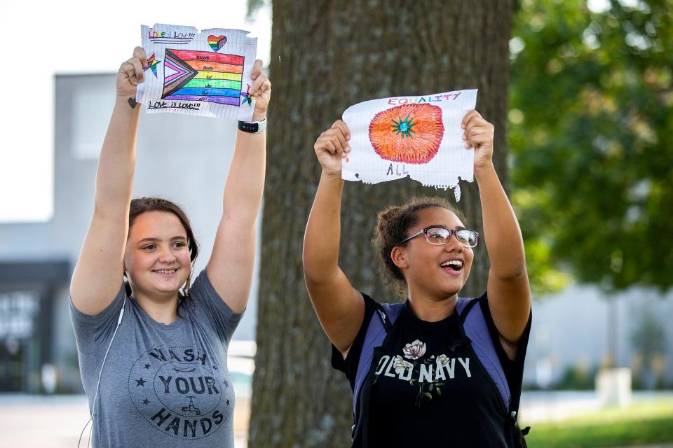 Winterset Junior High eight graders Dakota Clark and Amari Bonner hold homemade signs outside the school Tuesday to show support for Lucas Kaufmann, a teacher who was put on administrative leave after using an image of a pride flag in a presentation to share information about himself with his students.