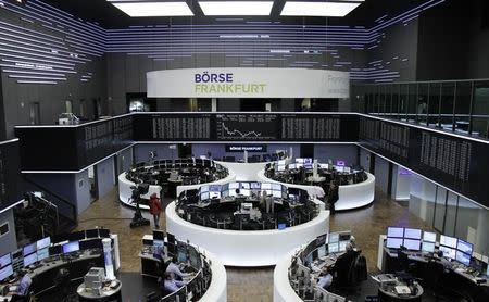 Traders work at their desks in front of the German share price index, DAX board, at the stock exchange in Frankfurt, Germany, January 9, 2017. REUTERS/Staff/Remote