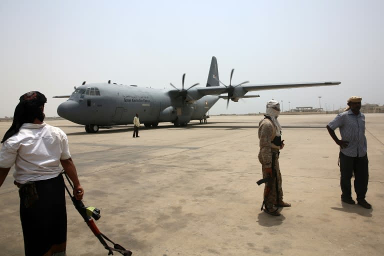 Yemeni fighters stand on the tarmac as a Qatari plane carrying relief aid arrives at Aden's international airport on August 1, 2015