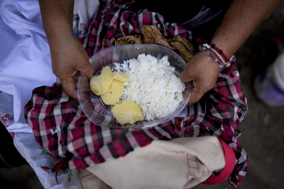 Street food vendor Margarita Vidal prepares a plate, that includes potatoes and rice, for delivery, amid rising inflation in Buenos Aires, Argentina, Thursday, March 16, 2023. (AP Photo/Natacha Pisarenko)