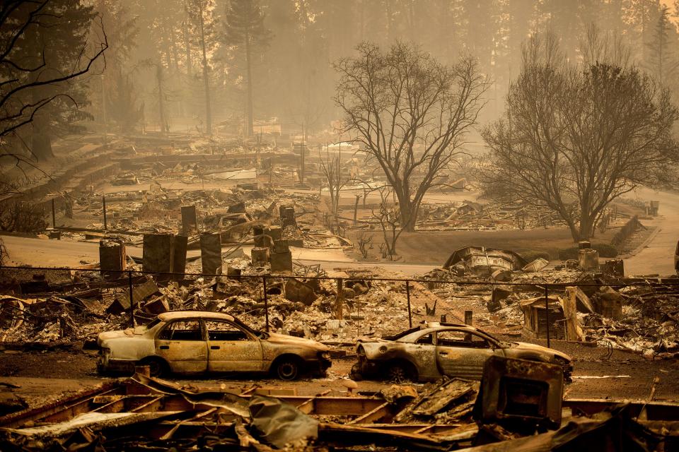 In this Monday, Nov. 12, 2018 file photo, homes leveled by the Camp Fire line a development on Edgewood Lane in Paradise, Calif. Rain in the forecast starting Wednesday, Nov. 21, could aid crews fighting Northern California's deadly wildfire while raising the risk of debris flows and complicating efforts to recover remains.