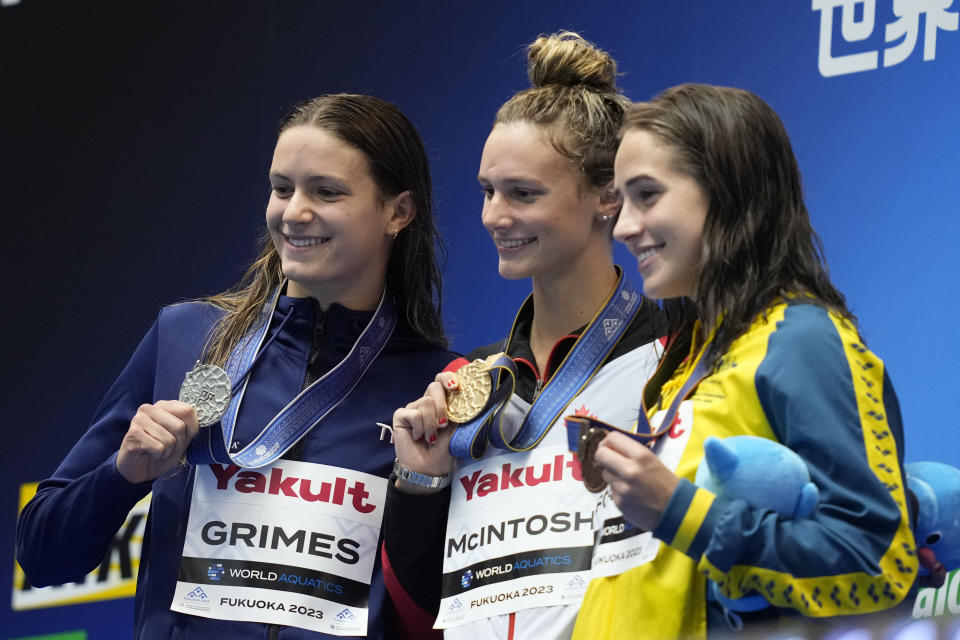 Medalists, from left to right, Katie Grimes of the U.S., silver, Summer McIntosh of Canada, gold, and Jenna Forrester of Australia, bronze celebrate during the medal ceremony for the women's 400m medley at the World Swimming Championships in Fukuoka, Japan, Sunday, July 30, 2023. (AP Photo/Eugene Hoshiko)