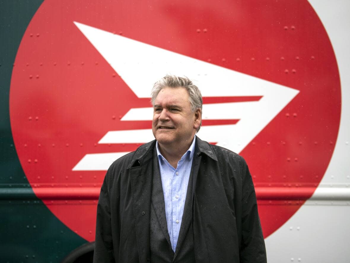 Canada Post CEO Doug Ettinger poses in front of an electric delivery vehicle after a news conference on the postal service’s plans to transform their fleet of 14,000 vehicles, in Ottawa, in June 2022. Getting rid of daily mail delivery is not an option Canada Post is considering, the Crown corporation’s president and CEO told MPs on Wednesday night. (Justin Tang/The Canadian Press - image credit)