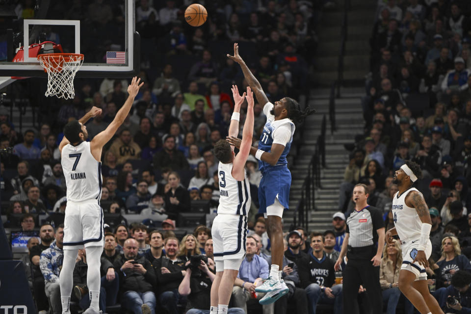 Minnesota Timberwolves center Naz Reid (11) takes a shot over Memphis Grizzlies forward Jake LaRavia (3) and forward Santi Aldama (7) during the first half of an NBA basketball game Wednesday, Feb 28, 2024, in Minneapolis. (AP Photo/Craig Lassig)