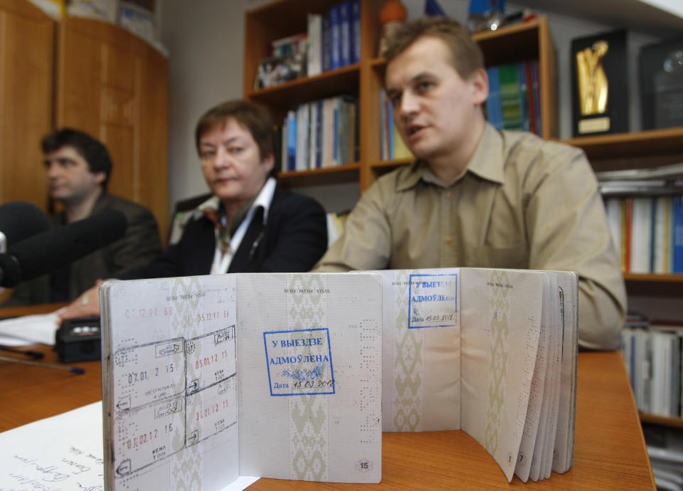 FILE - Zhanna Litvina, the head of the Belarusian Association of Journalists, center, and Mikhas Yanchuk, a journalist of the Belsat channel, right, show their passports with a stamp that bans them leaving the country during a news conference in Minsk, Belarus, Thursday, March 15, 2012. Belarus has stopped renewing passports at its embassies abroad, and hundreds of thousands of Belarusians who have fled President Alexander Lukashenko's repressive regime cannot update their travel documents without returning home and risking possible arrest. (AP Photo/File)