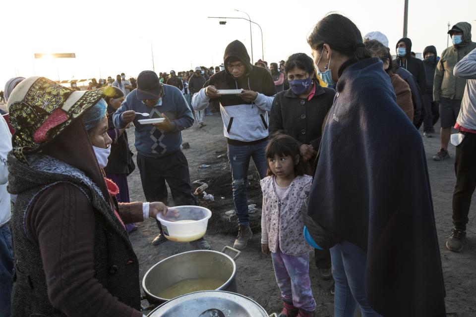 Farmworkers eat breakfast as they block the Pan-American South Highway on the fourth day of protests against the Agricultural Promotion Law, in Villacuri, Ica province, Peru, Thursday, Dec. 3, 2020. The workers are asking for the elimination of a law, demanding better wages and health benefits. (AP Photo/Rodrigo Abd)