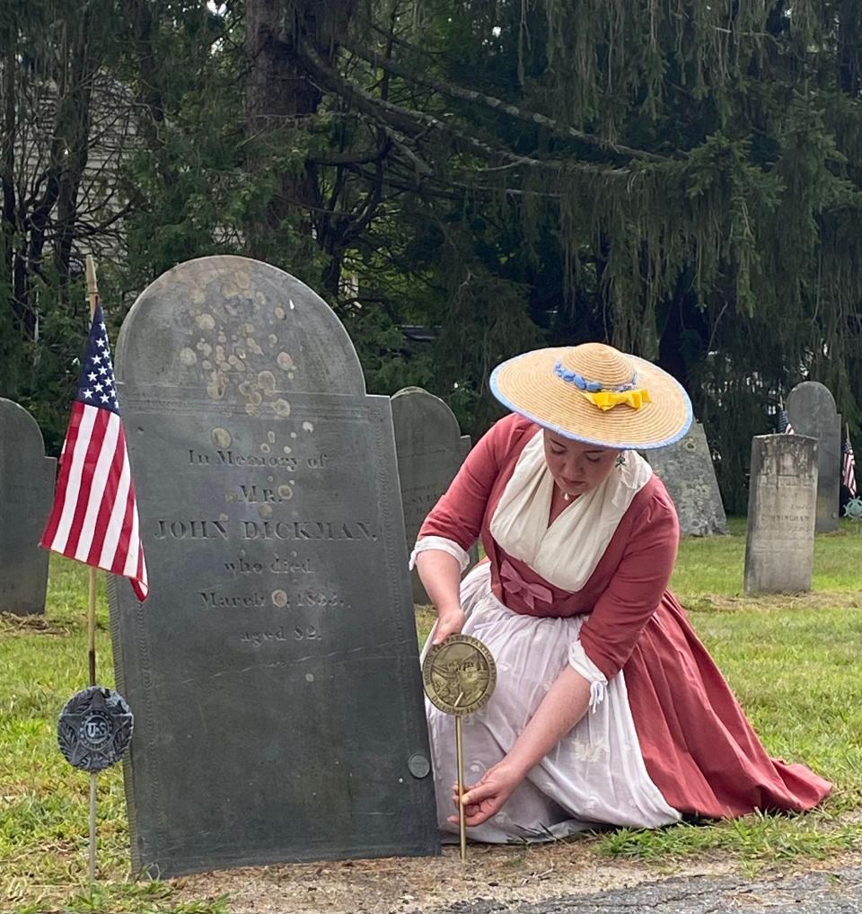 Danielle Pribyl, of the Boston Tea Party Ships Museum, adds a commemorative plaque to the grave of John Dickman on Aug. 27 at Evergreen Cemetery in Hopkinton.