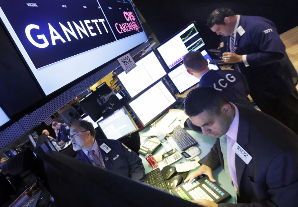 FILE - In this Aug. 5, 2014, file photo, specialist Michael Cacace, foreground right, works at the post that handles Gannett on the floor of the New York Stock Exchange. GateHouse Media closed on its takeover of Gannett Tuesday, Nov. 19, 2019, becoming the country’s largest newspaper company by far at a time when print publications are in precipitous decline. (AP Photo/Richard Drew, File)