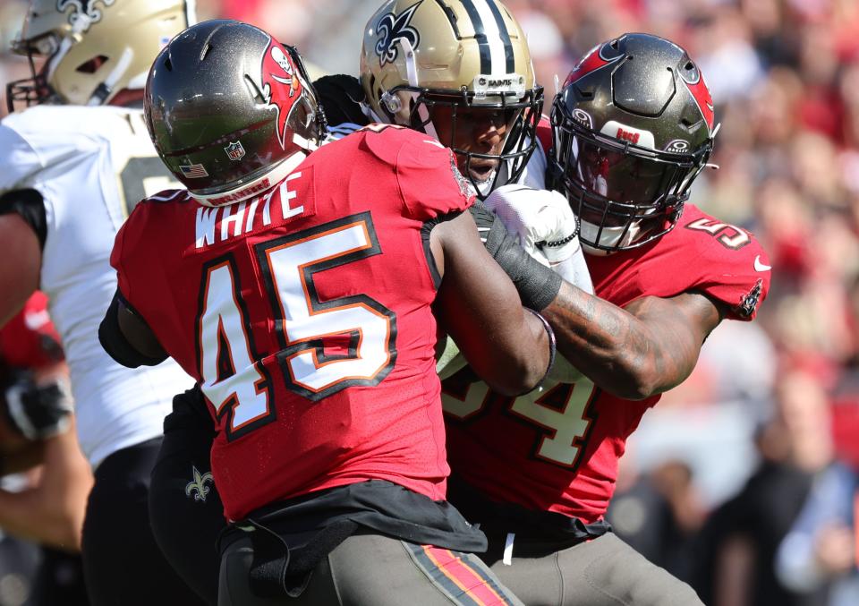 New Orleans Saints running back Jamaal Williams (21) runs with the ball as Tampa Bay Buccaneers linebacker Devin White (45) and linebacker Lavonte David (54) tackle during the first quarter at Raymond James Stadium.