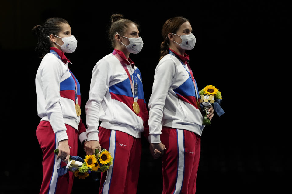 Hand by hand, gold medalists Russian Olympic committee Sabre team listen to the Russian Olympic Committee anthem during the medal ceremony for the women's Sabre team final medal competition at the 2020 Summer Olympics, Saturday, July 31, 2021, in Chiba, Japan. (AP Photo/Hassan Ammar)