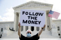 Bill Christeson holds up a sign that reads "Follow the Money" outside the Supreme Court, Thursday, July 9, 2020, in Washington. The Supreme Court ruled Thursday that the Manhattan district attorney can obtain Trump tax returns while not allowing Congress to get Trump tax and financial records, for now, returning the case to lower courts. (AP Photo/Andrew Harnik)