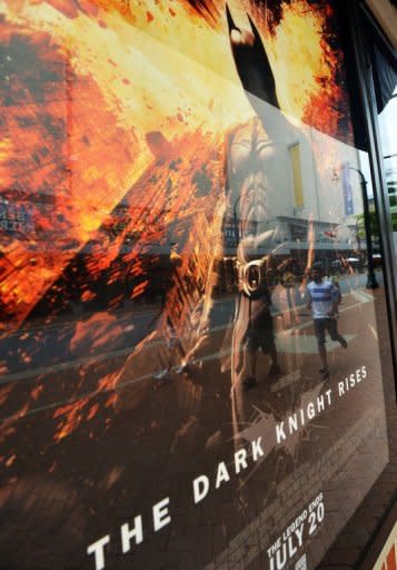 People walk past a poster of the new Batman movie "The Dark Knight Rises" outside a theater in Silver Spring, Maryland. With a fixation on random violence, Gotham City dysfunction and the death of a star, the "Batman" movies have long been consumed with tragedy and terror. Now an unfathomable horror is forever linked to the series