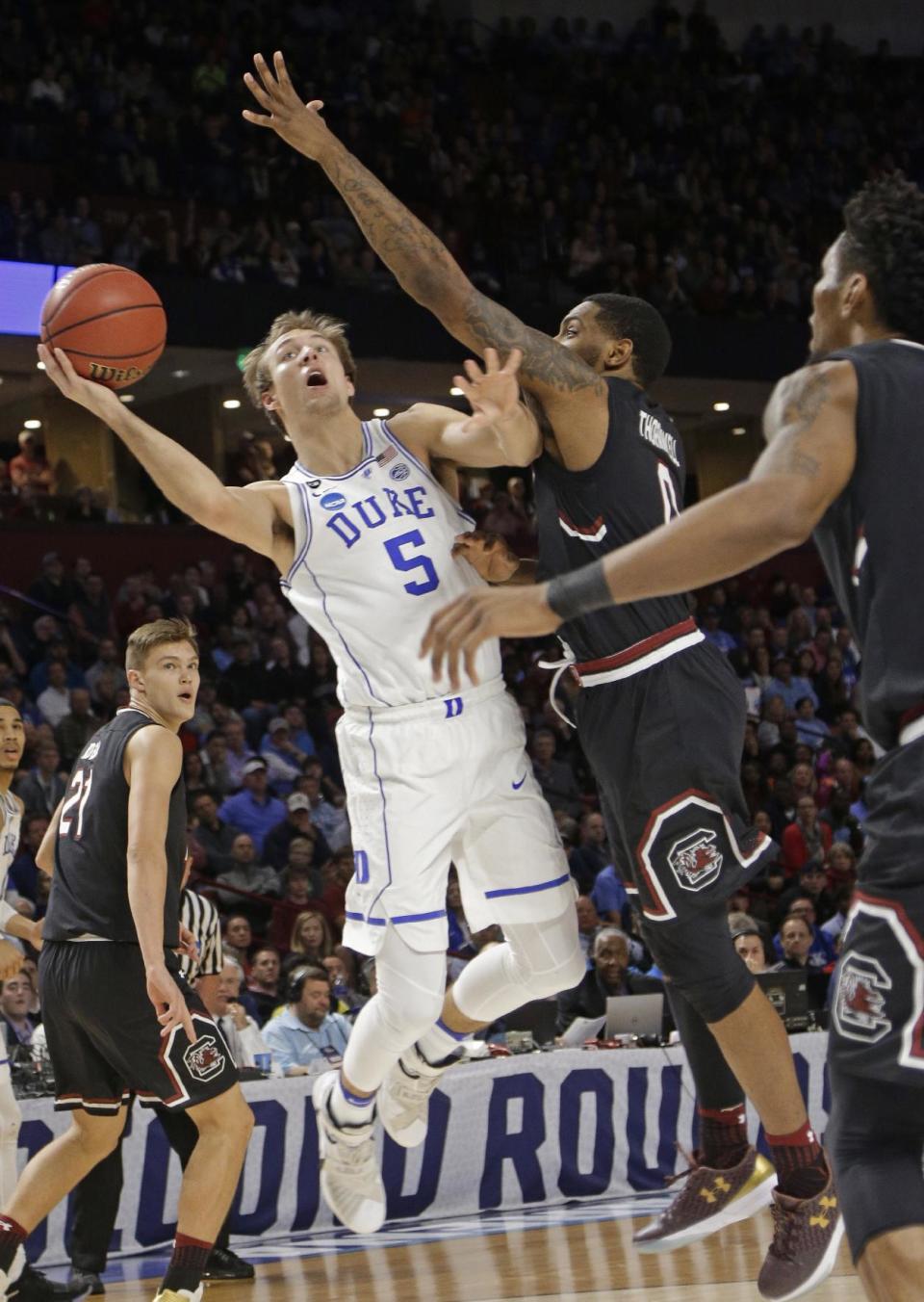 Duke's Luke Kennard (5) is fouled as he drives against South Carolina's Sindarius Thornwell (0) during the second half in a second-round game of the NCAA men's college basketball tournament in Greenville, S.C., Sunday, March 19, 2017. (AP Photo/Chuck Burton)