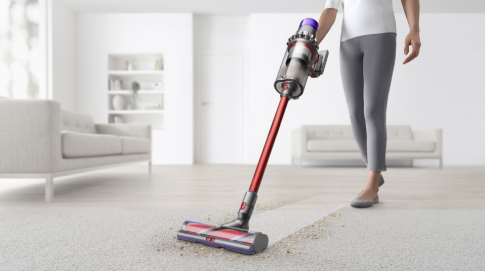 Woman using a Dyson Outsize Total Clean stick vacuum