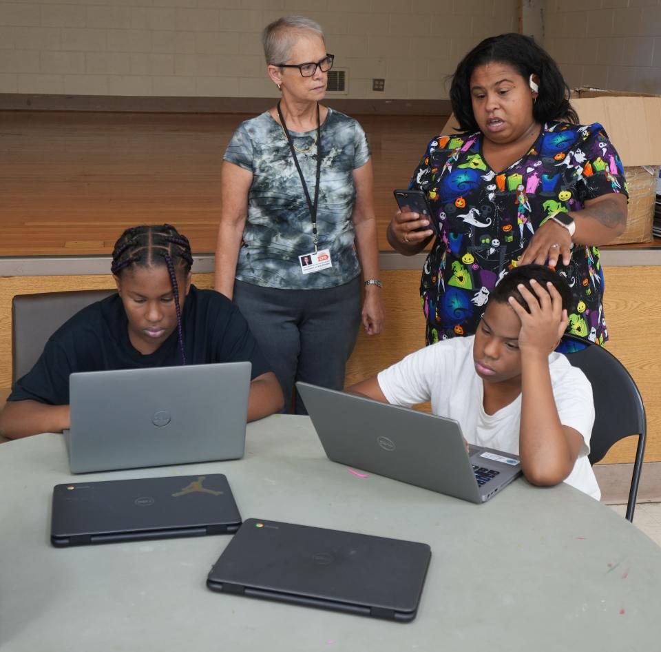 As the Columbus City Schools teacher strike moves into the third day, Community for New Directions staffer Renee Blackford listens to Ashley Shepherd as she works out computer issues with her children, Ava (left) and Jaisun Bronson. They were at Barack Community Center on the South Side.