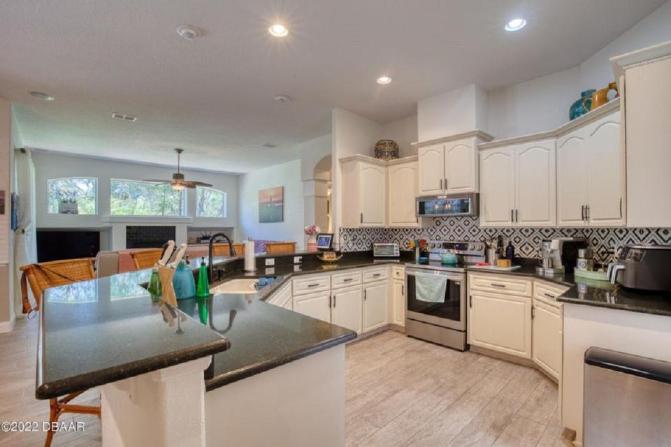 The kitchen offers quartz countertops, stainless-steel appliances and a breakfast bar, overlooking the family room with its centerpiece fireplace and large window.