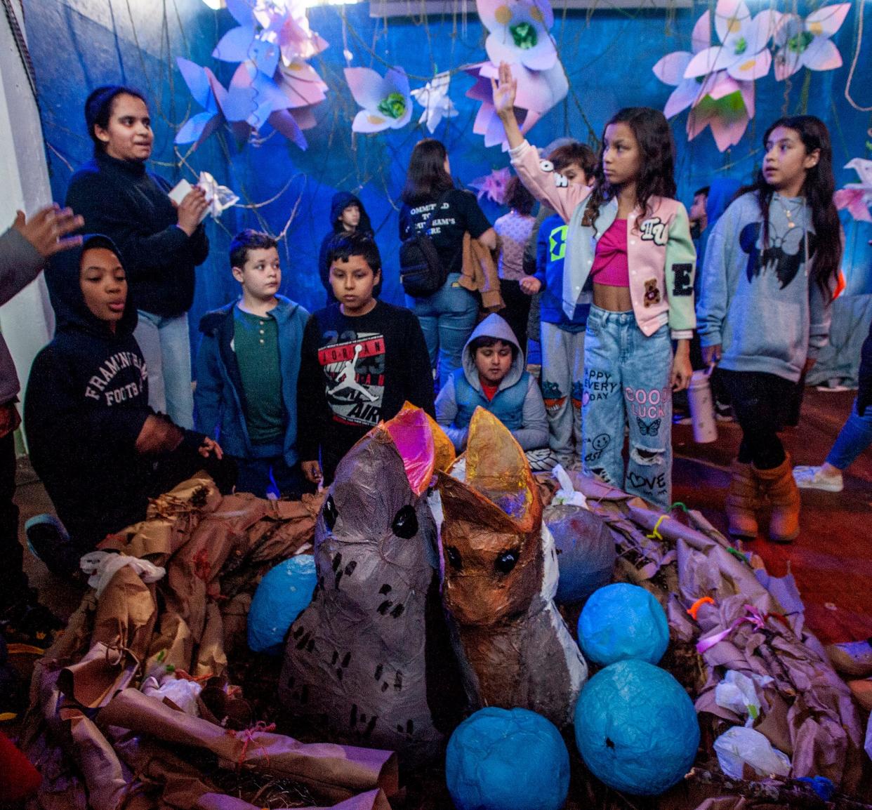 Hiranmayi Narasimhan, standing at left, a Framingham High School junior and member of the Environmental Awareness Club, gives a guided tour of the club's interactive climate-themed art gallery at the Saxonville Mills to fifth graders from the McCarthy Elementary School, March 12, 2024. The exhibit focuses on flooding, invasive aquatic plants, specise decline and coral bleaching.