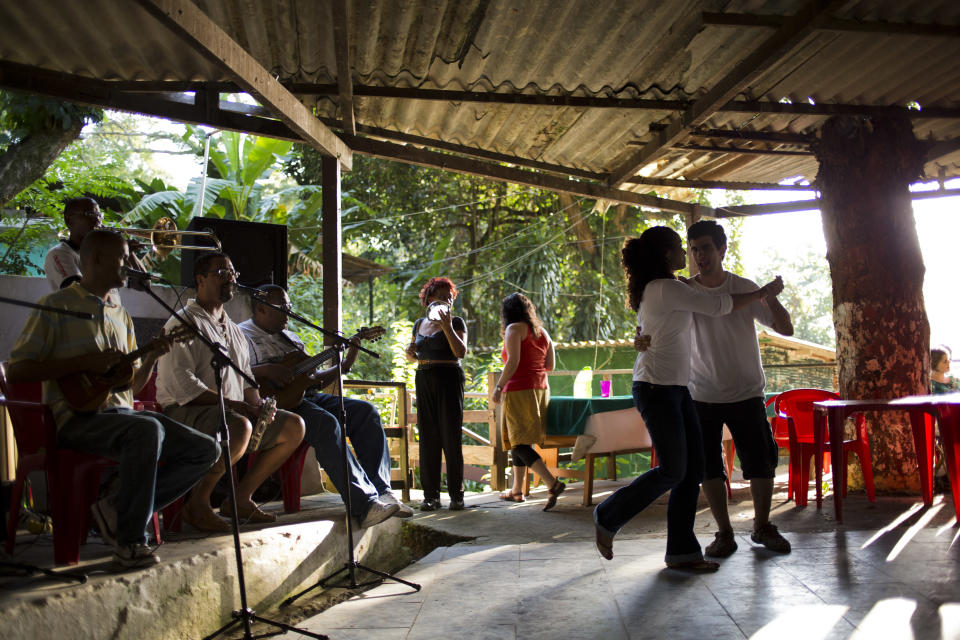 In this Sept. 15, 2012 photo, a couple dances to live samba music at the Quilombo Sacopa in Rio de Janeiro, Brazil. Quilombos are communities founded by escaped slaves or their descendents, and in Sacopa, the community is trying to save the grouping of brick houses and shacks nestled in the lush foilage of Brazil’s coastal rainforest where families have made their home for more than century but never legally owned. (AP Photo/Victor R. Caivano)