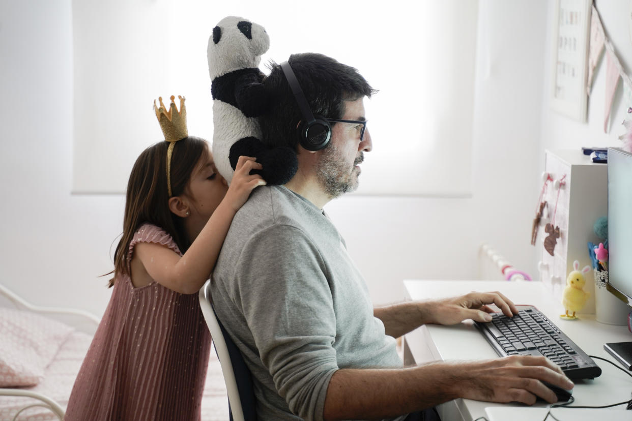 Middle-aged men working from home with kid. (Getty Images)