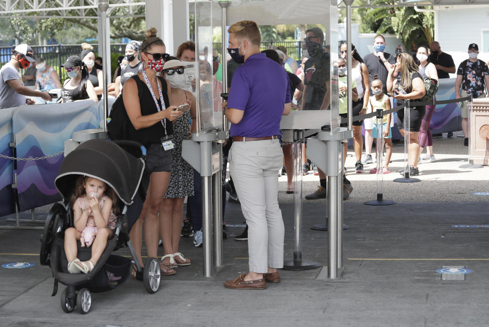 Guests enter SeaWorld as it reopens with new safety measures in place because of the coronavirus pandemic, Thursday, June 11, 2020, in Orlando, Fla. The park had been closed since mid-March to stop the spread of the new coronavirus. (AP Photo/John Raoux)