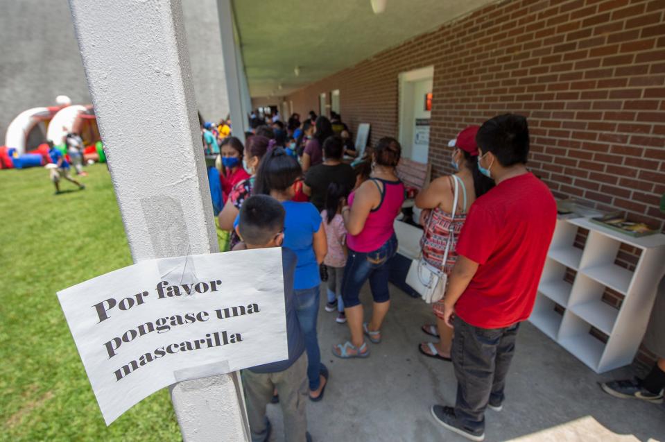 El Pueblo, a nonprofit specializing in immigration legal services, is ready with masks and hand sanitizer for people in line for school supplies during a school supply distribution at Trinity Mission Center in Forest, Miss., a Saturday, July 11, 2020. In August 2019, the Latino community was hard hit by ICE raids at local poultry plants. The event was hosted by El Pueblo in cooperation with Sugartown Riders Motorcycle Club from Kosciusko, Miss.