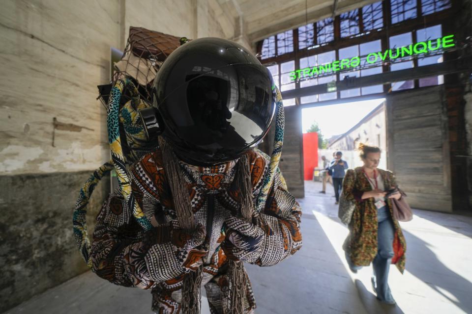 A visitor walks next to the installation "Refugee Astronaut VIII," by artist Yinka Shonibare at the 60th Biennale of Arts exhibition in Venice, Italy, Tuesday, April 16, 2024. The Venice Biennale contemporary art exhibition opens Saturday for its six-month run through Nov. 26. The main show titled "Stranieri Ovunque – Foreigners Everywhere," is curated for the first time by a Latin American, Brazilian Adriano Pedrosa. Alongside the main exhibition, 88 national pavilions fan out from the traditional venue in Venice's Giardini, to the Arsenale and other locations scattered throughout the lagoon city. (AP Photo/Luca Bruno)