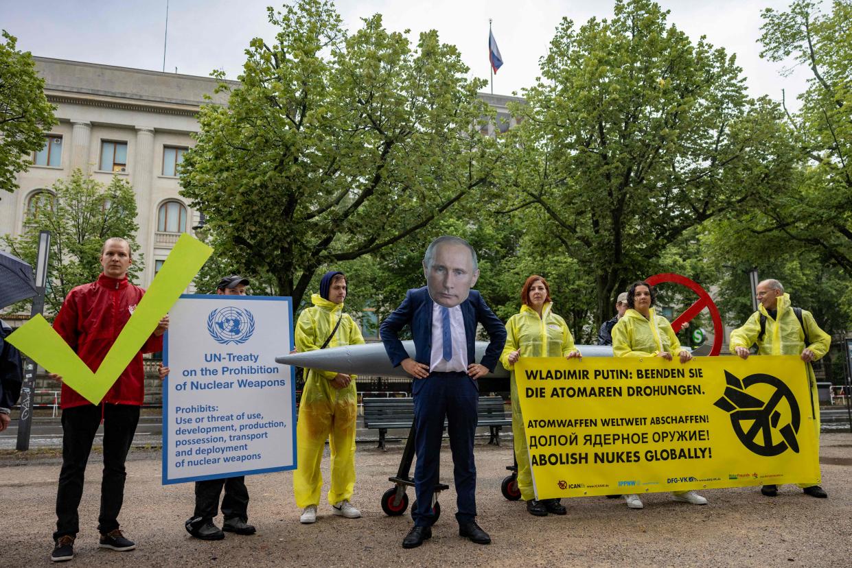 An activist wearing a mask of Russia&#39;s President Vladimir Putin stands next to fellow activists of the IPPNW (International Physicians for the Prevention of Nuclear War) peace organisation holding up a poster depciting a copy of the UN Treaty on the Prohibition of Nuclear Weapons and a banner that reads &#x00201c;Vladimir Putin: End the nuclear threats&#x00201d; (AFP via Getty Images)