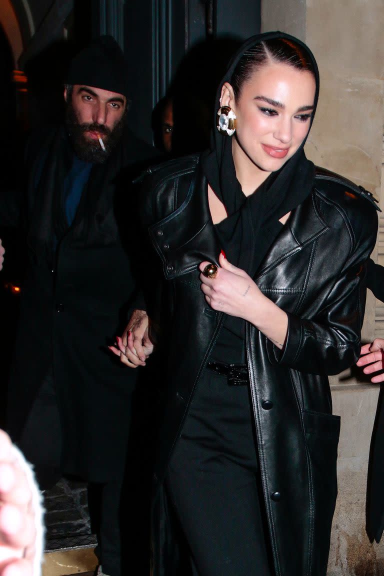 Dua Lipa asiste al desfile Otoño Invierno 2023-2024 de Saint Laurent Womenswear como parte de la Semana de la Moda de París en París, Francia. La artista luce un atuendo totalmente negro con un vestido con capucha cruzado en el cuello y un trench de cuero