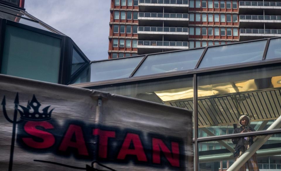 An onlooker watches people who are protesting SatanCon at Copley Place in Boston, Mass., on April 28, 2023.