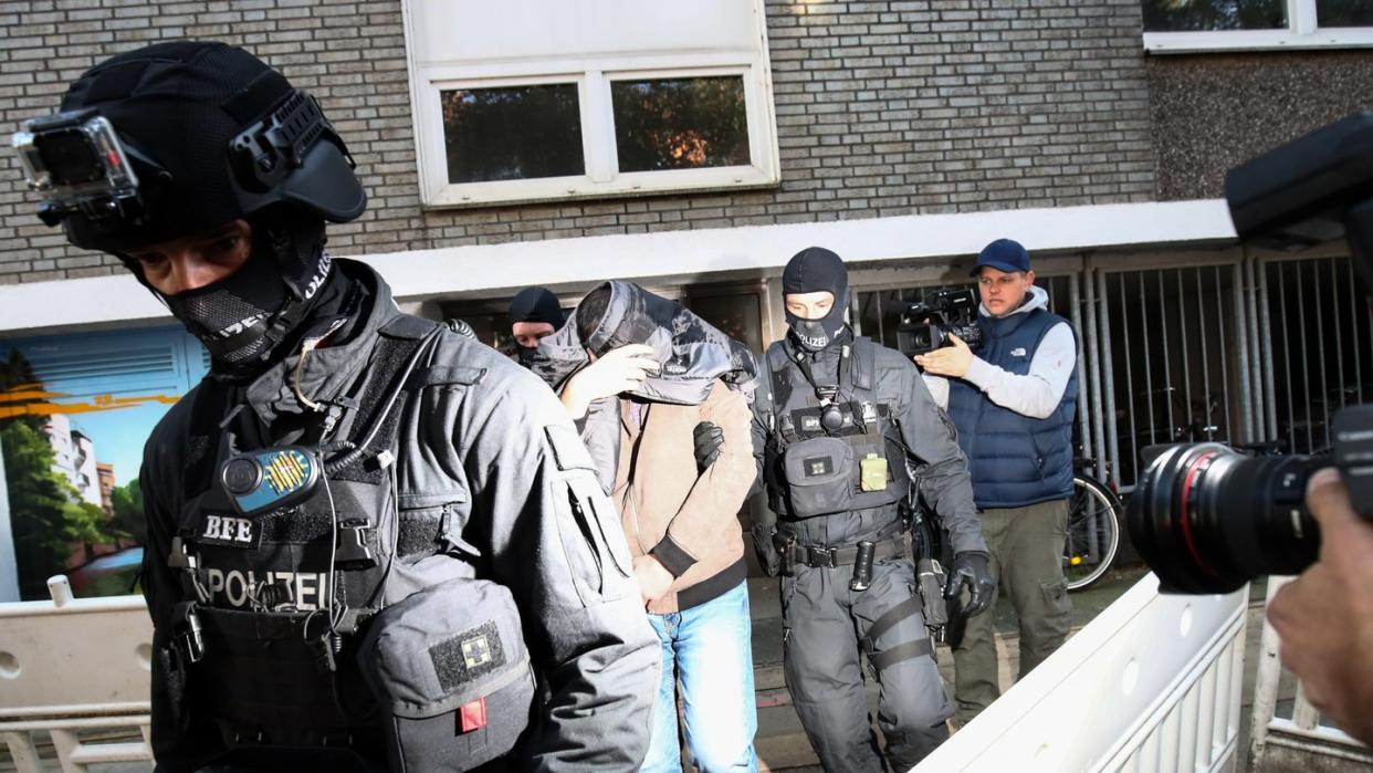 Terror-Razzia in Hamburg: Ein Mann wird von Polizisten aus einem Haus geführt. Foto: Christian Charisius