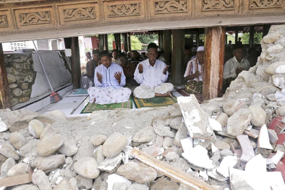 Survivors perform Friday prayer at a mosque badly damaged by Wednesday's earthquake in Pidie, Aceh province, Indonesia, Friday, Dec. 9, 2016. Over one hundred people were killed in the quake that hit the northeast of the province on Sumatra before dawn Wednesday. Hundreds of people were injured and thousands buildings destroyed or heavily damaged. (AP Photo/Heri Juanda)