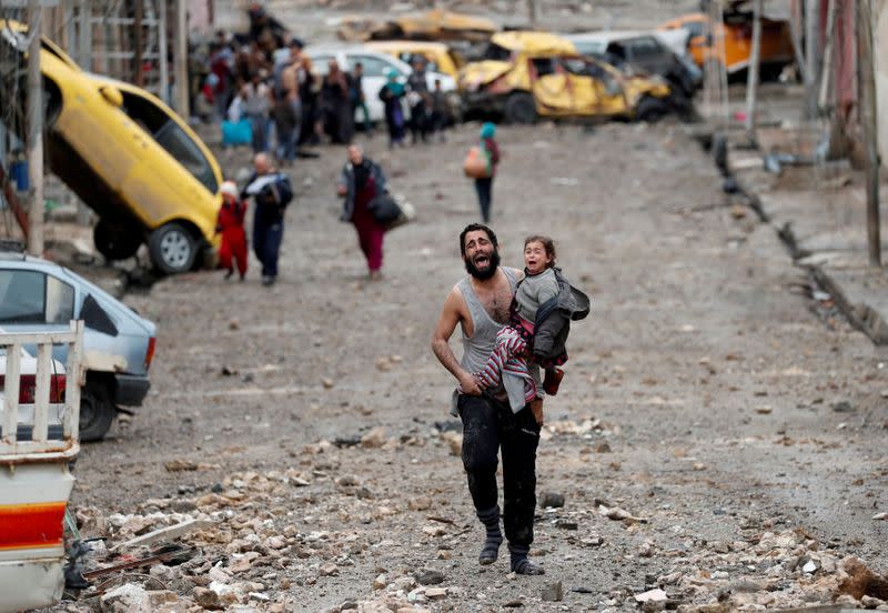 FILE PHOTO: A man cries as he carries his daughter while walking from an Islamic State controlled part of Mosul