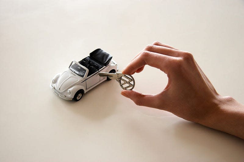 A miniature classic VW beetle cabriolet with a real VW key pretending to unlock the door