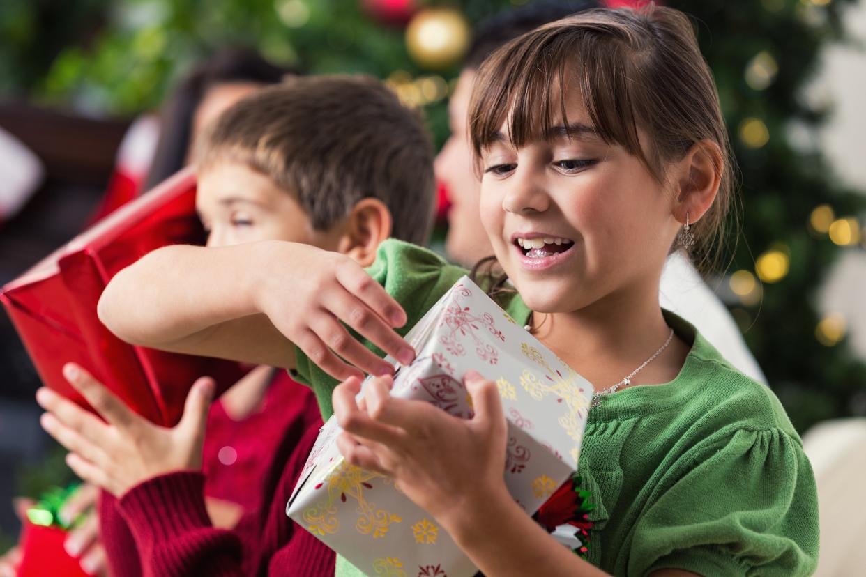 little girl opening up a present during Christmas with family