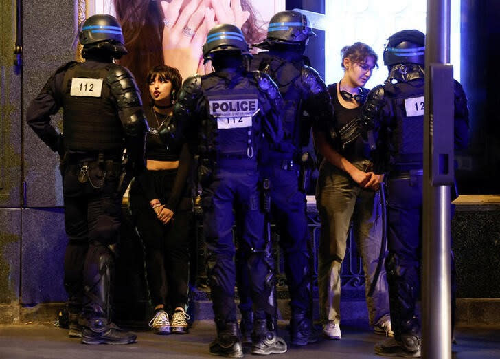 Oficiales de policía hablan con mujeres mientras la gente protesta cerca de la Ópera Garnier, luego de la muerte de Nahel, una adolescente de 17 años a manos de un policía en Nanterre, en París, Francia