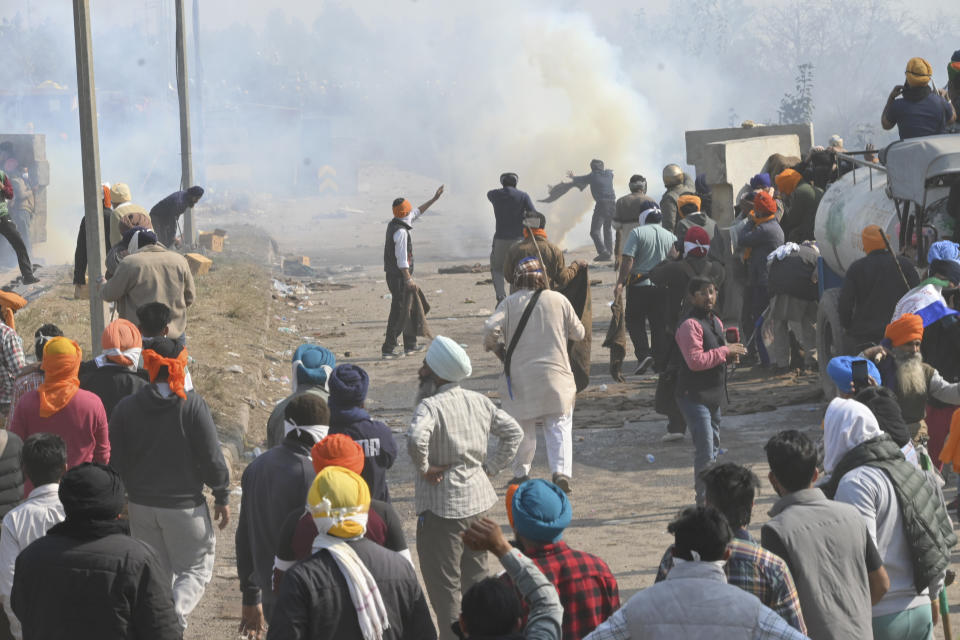 Farmers react after police fired tear gas at protesting farmers near Shambhu border that divides northern Punjab and Haryana states, almost 200 km (125 miles) from New Delhi, India, Wednesday, Feb.14, 2024. Protesting Indian farmers Wednesday clashed with police for a second consecutive day as tens of thousands of them tried to march to the capital New Delhi to demand guaranteed crop prices for their produce. (AP Photo/Rajesh Sachar)