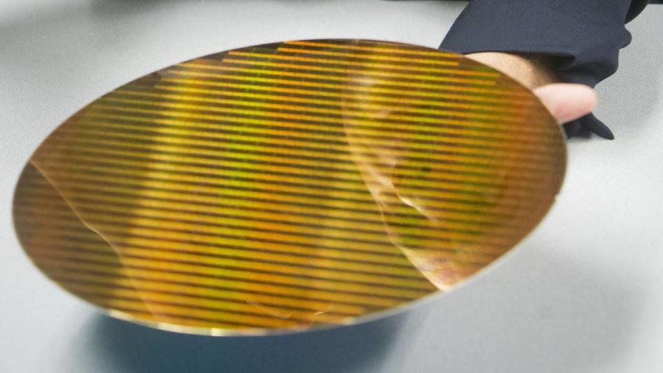 A Micron Technology Inc. executive’s face is reflected in a 12-inch wafer from which memory chips are cut. 